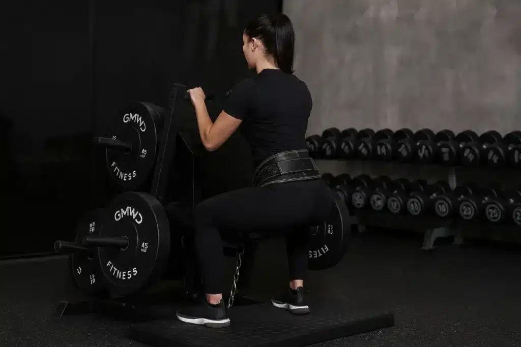 Woman performing squats using a belt squat machine in a gym